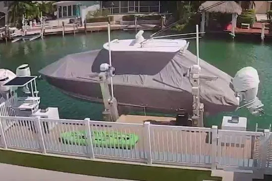  Yacht Photos Pics Covered 2023 Jupiter 32 boat docked by waterfront with white fence and green kayak.