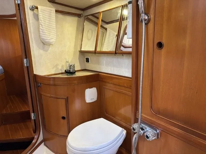 Seacape Yacht Photos Pics 1996 Hylas 46 yacht bathroom with wooden cabinetry, mirror, and white toilet.