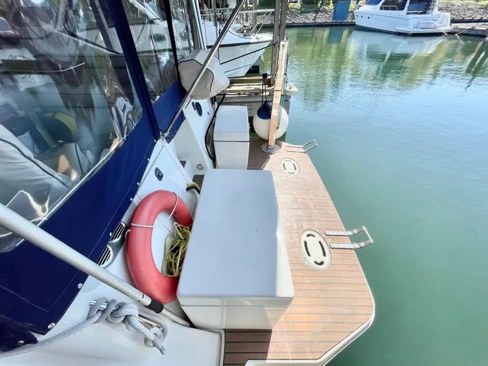 Hailey Brae Yacht Photos Pics 2021 Custom Express Cruiser docked, featuring a wooden deck and safety equipment.