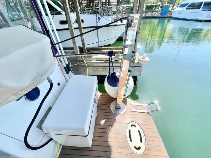 Hailey Brae Yacht Photos Pics 2021 Custom Express Cruiser docked, featuring a cushioned seat and wooden deck.