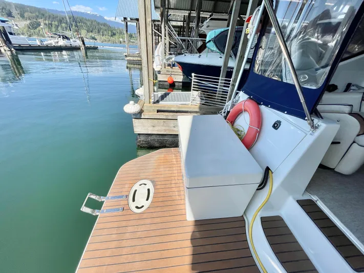 Hailey Brae Yacht Photos Pics 2021 Custom Express Cruiser docked, featuring a wooden deck and life preserver, in a serene marina setting.