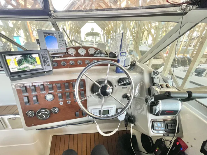 Hailey Brae Yacht Photos Pics 2021 Custom Express Cruiser helm with navigation instruments and steering wheel in a marina setting.
