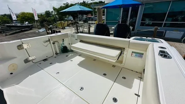 Yacht Photos Pics 2023 Boston Whaler 325 boat deck with seating, docked near umbrellas and a building.
