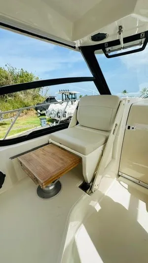  Yacht Photos Pics 2023 Boston Whaler 325 interior with seating and wooden table, showcasing luxury design.