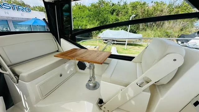 Yacht Photos Pics Interior of 2023 Boston Whaler 325 boat with seating and wooden table.