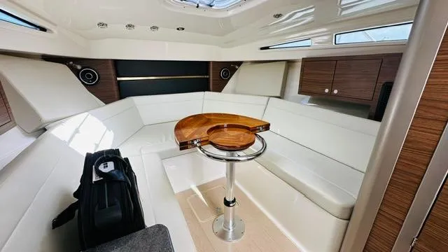 Yacht Photos Pics 2023 Boston Whaler 325 cabin interior with white seating, wooden accents, and a central table.