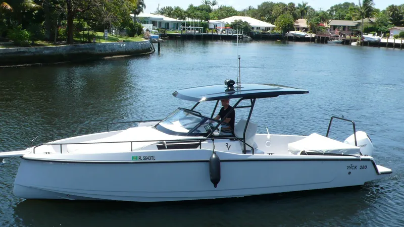  Yacht Photos Pics 2023 RYCK 28 boat cruising on a calm river with waterfront homes in the background.
