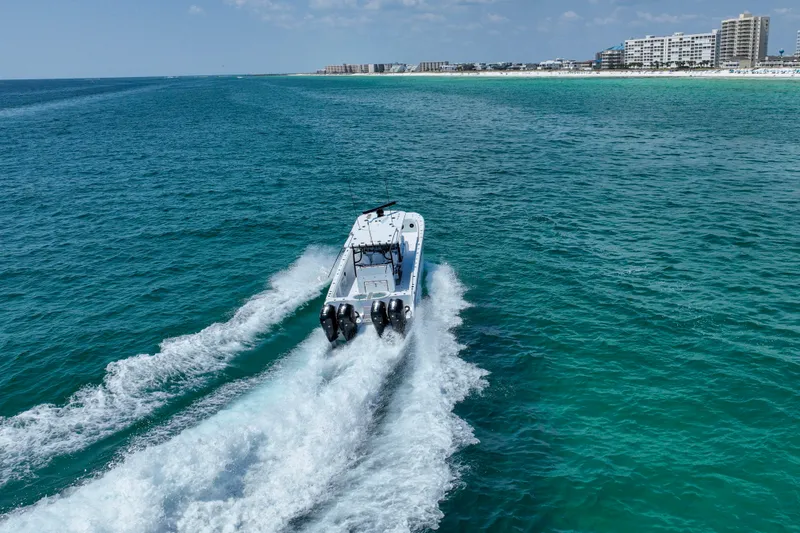  Yacht Photos Pics 2026 Invincible 40 Catamaran cruising on turquoise ocean near coastline.