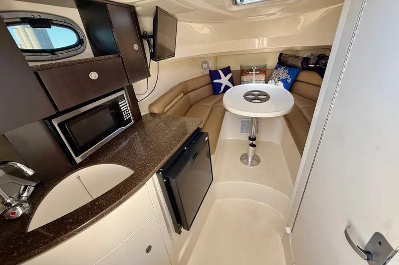  Yacht Photos Pics 2007 Boston Whaler 285 Conquest cabin interior with kitchenette, seating, and table.