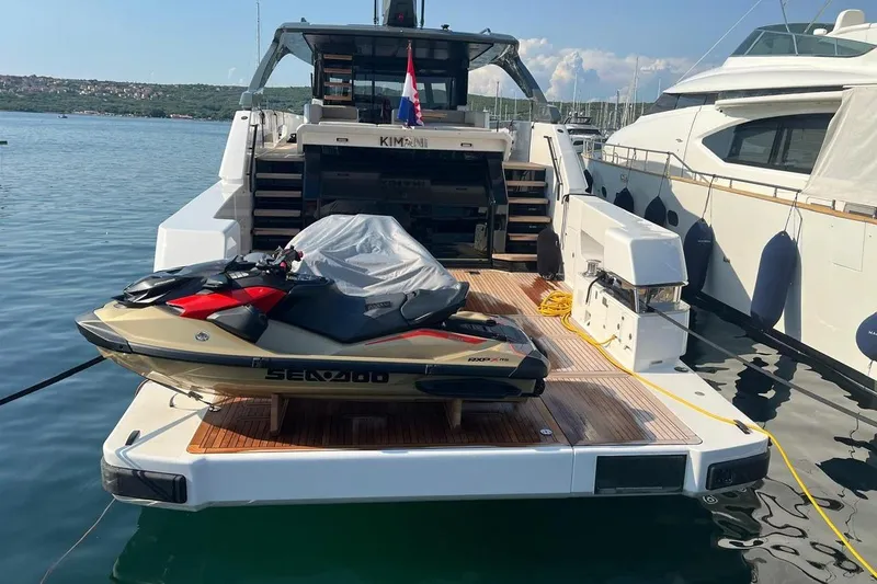  Yacht Photos Pics 2025 Bluegame BG74 yacht with jet ski on deck, docked at marina.