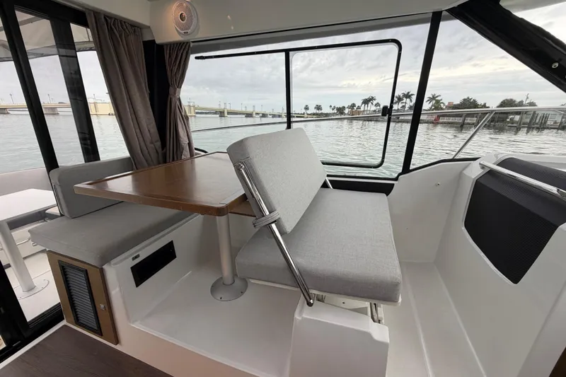  Yacht Photos Pics Interior of 2019 Jeanneau NC 895 boat with seating and table, overlooking water.
