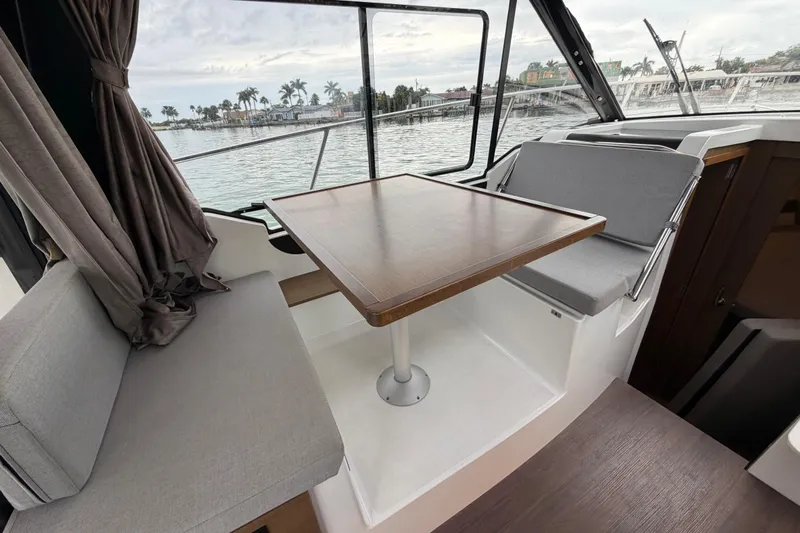  Yacht Photos Pics 2019 Jeanneau NC 895 interior with seating and table, overlooking marina view.