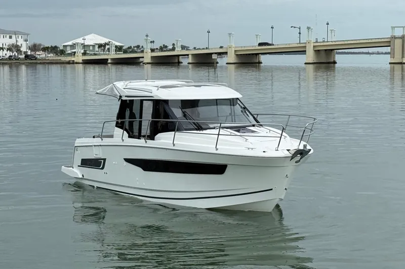  Yacht Photos Pics 2019 Jeanneau NC 895 boat on calm water near a bridge.