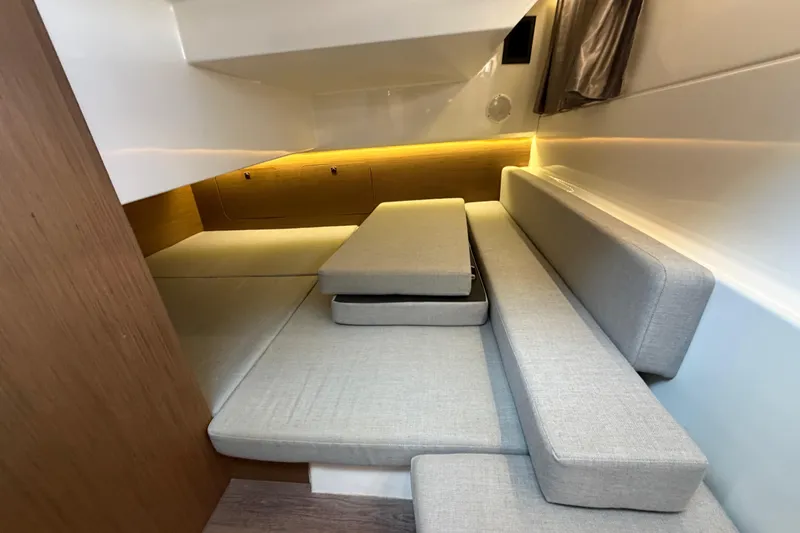  Yacht Photos Pics 2019 Jeanneau NC 895 interior cabin with gray cushions and wooden accents.