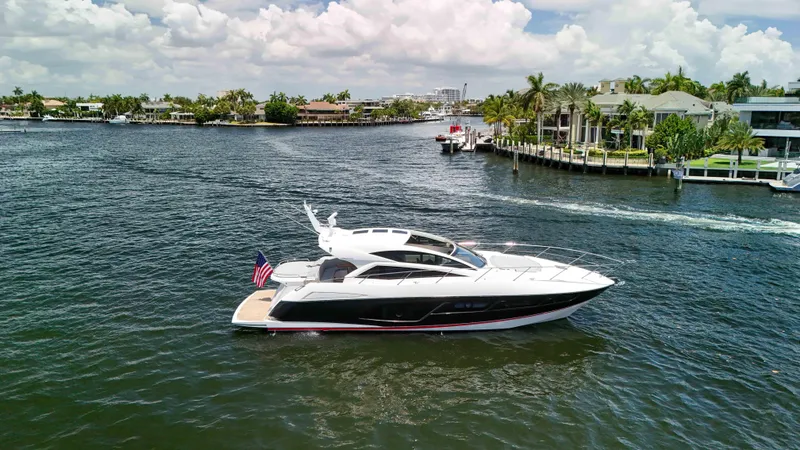 Arbitrage Yacht Photos Pics 2017 Sunseeker Predator 57 yacht cruising on a scenic waterway with luxury homes.