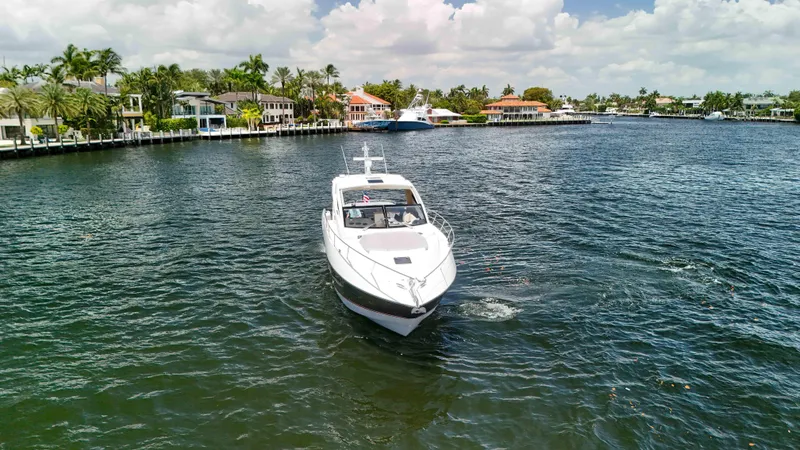 Arbitrage Yacht Photos Pics 2017 Sunseeker Predator 57 yacht cruising near waterfront homes under a cloudy sky.