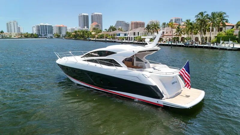 Arbitrage Yacht Photos Pics 2017 Sunseeker Predator 57 yacht cruising near waterfront cityscape with palm trees.