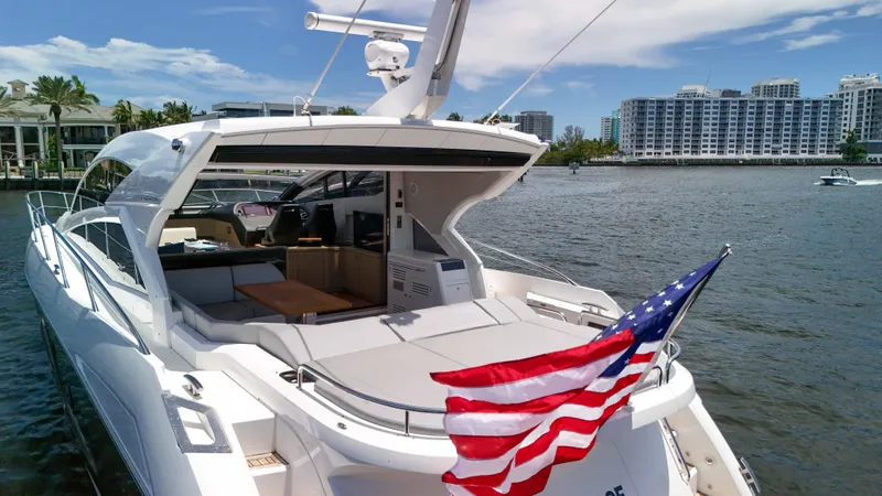 Arbitrage Yacht Photos Pics 2017 Sunseeker Predator 57 yacht with American flag, docked near waterfront buildings.
