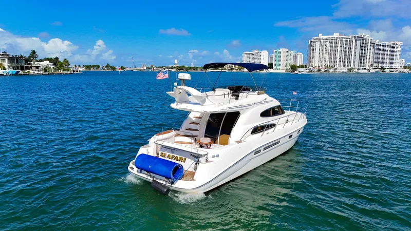 Seafari Yacht Photos Pics 2004 Sealine 47 yacht cruising on blue waters with city skyline in the background.