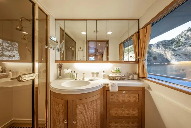  Yacht Photos Pics Luxurious bathroom on 1982 Feadship Classic yacht with elegant wood cabinetry and scenic window view.