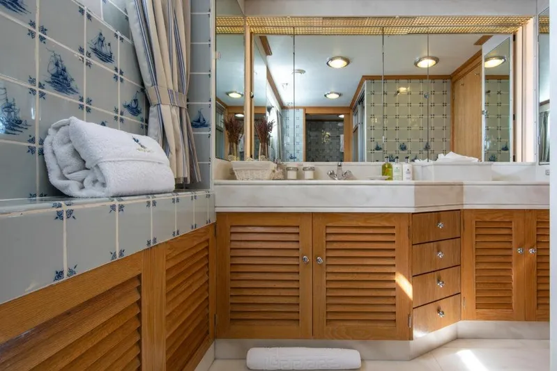  Yacht Photos Pics Luxurious bathroom on 1982 Feadship Classic yacht with nautical-themed tiles and wooden cabinetry.