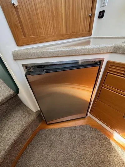 Island Dreamer Yacht Photos Pics 1999 Riviera Convertible interior with compact stainless steel fridge and wooden cabinetry.