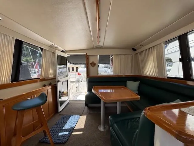Island Dreamer Yacht Photos Pics 1999 Riviera Convertible yacht interior with dining area, green seating, and wooden accents.