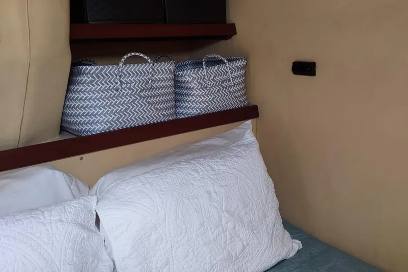 Nyango Yacht Photos Pics Cozy cabin interior of 1996 Fountaine Pajot Venezia 42 with white pillows and storage baskets.