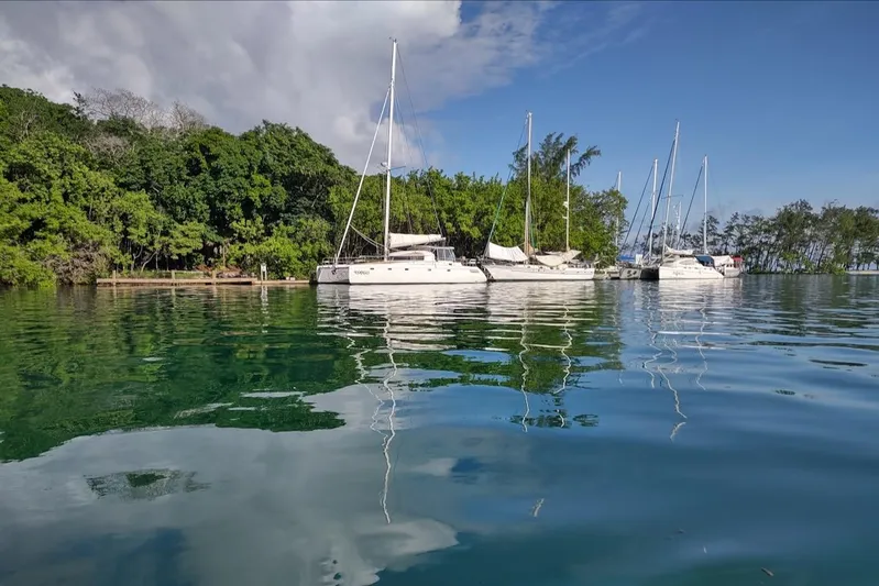 Nyango Yacht Photos Pics Sailboats, including a 1996 Fountaine Pajot Venezia 42, anchored near lush green shoreline.