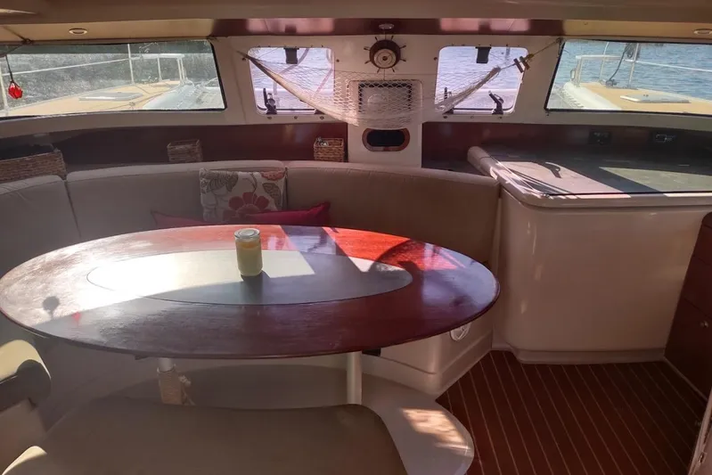 Nyango Yacht Photos Pics Interior of 1996 Fountaine Pajot Venezia 42 catamaran with wooden table and seating area.