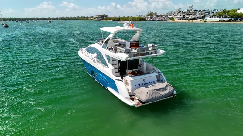 Fortunato Yacht Photos Pics Azimut 50 Flybridge 2016 yacht cruising on clear green waters near a scenic shoreline.