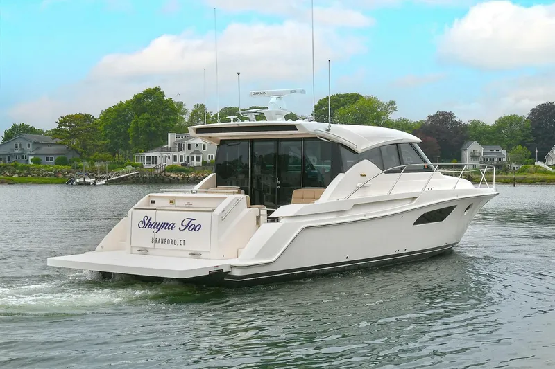  Yacht Photos Pics 2015 Tiara Yachts C44 Coupe cruising on a serene lake with waterfront homes.