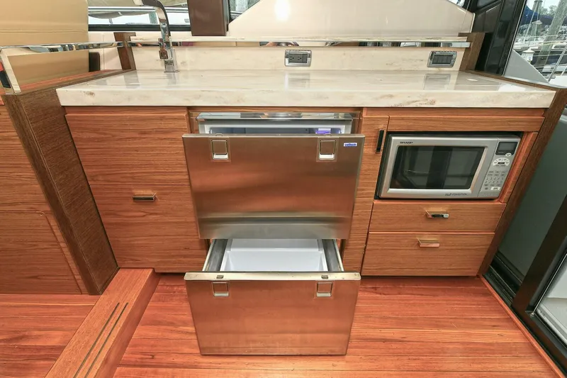  Yacht Photos Pics 2015 Tiara Yachts C44 Coupe kitchen with stainless steel appliances and wooden cabinetry.