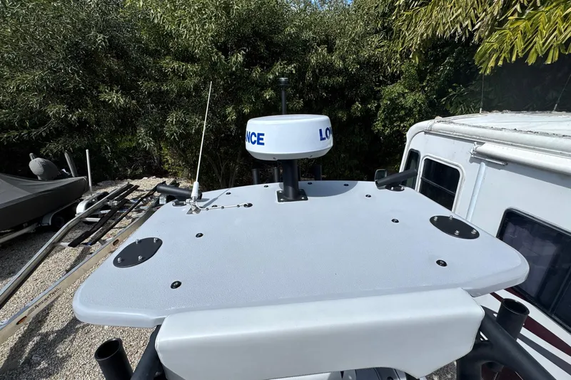  Yacht Photos Pics 2026 Yellowfin 24 Bay CE boat with radar equipment, surrounded by trees and trailers.