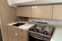 2024 Bavaria C38 yacht kitchen with modern sink, stove, and wooden cabinetry.