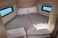 Cozy cabin interior of 2024 Bavaria C38 yacht with comfortable bedding and sea view windows.
