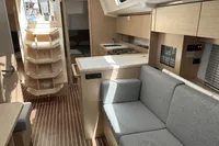 2024 Bavaria C38 yacht interior with modern kitchen, cozy seating, and wooden flooring.