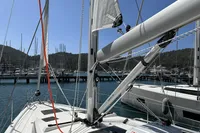2024 Bavaria C38 sailboat docked at marina, surrounded by clear blue water and distant hills.