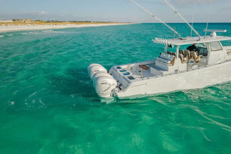 Just Looking Yacht Photos Pics 2024 Freeman 47 boat cruising in clear turquoise waters near a sandy beach.