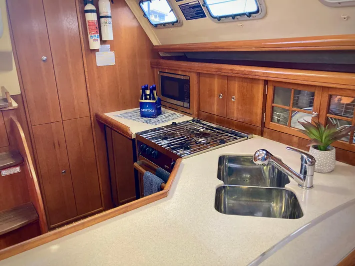 Light Seeker Yacht Photos Pics Interior of 2005 Hunter 41 AC yacht kitchen with stove, sink, and wooden cabinetry.