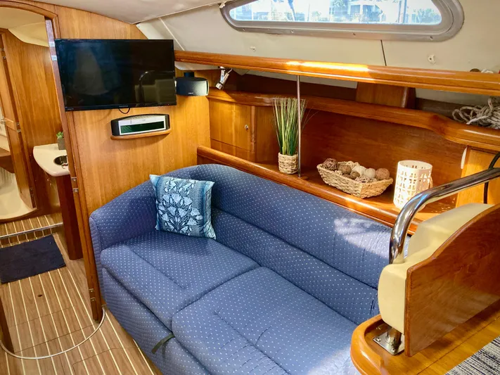 Light Seeker Yacht Photos Pics Interior of 2005 Hunter 41 AC yacht with blue sofa, TV, and wooden cabinetry.