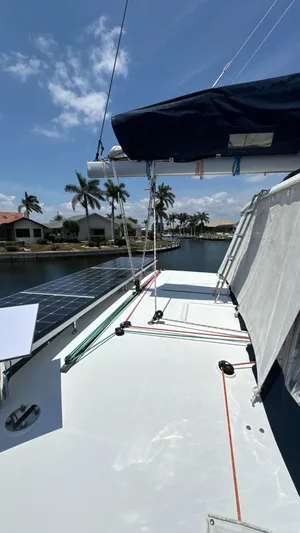 Aquamarine Yacht Photos Pics 2013 Lagoon 450 F catamaran deck with solar panels, docked by palm trees under a clear sky.