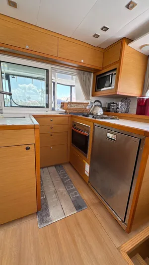 Aquamarine Yacht Photos Pics Modern kitchen interior of 2013 Lagoon 450 F yacht with wood cabinetry and stainless steel appliances.