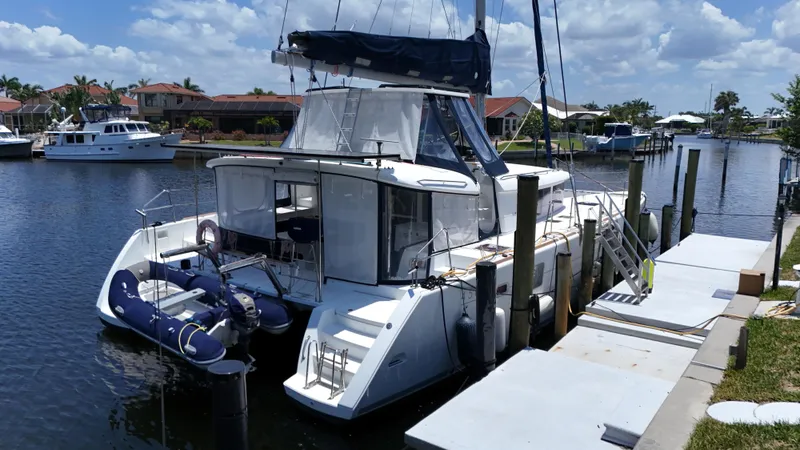Aquamarine Yacht Photos Pics 2013 Lagoon 450 F catamaran docked in a sunny marina, featuring a small inflatable boat.