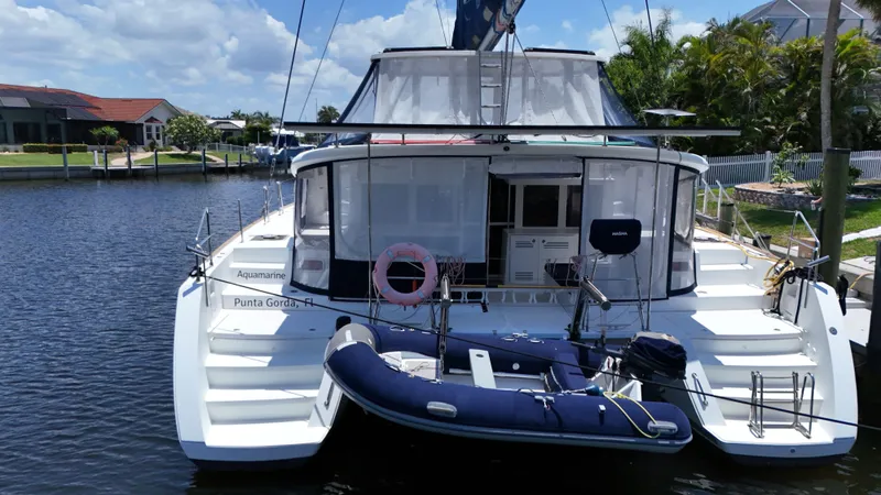 Aquamarine Yacht Photos Pics 2013 Lagoon 450 F catamaran docked with inflatable boat, sunny day, waterfront view.
