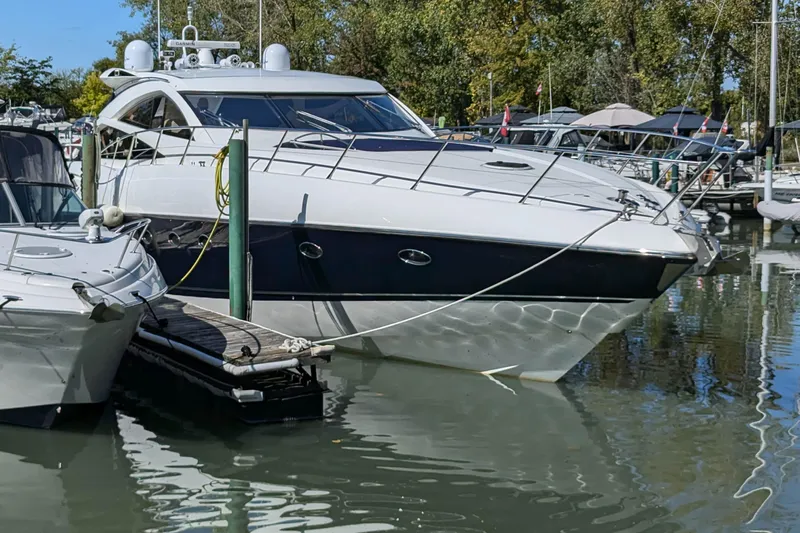  Yacht Photos Pics 2006 Sunseeker Predator 68 yacht docked in a marina, surrounded by trees and other boats.