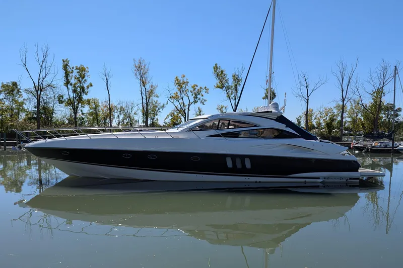  Yacht Photos Pics 2006 Sunseeker Predator 68 yacht on calm water, surrounded by trees.