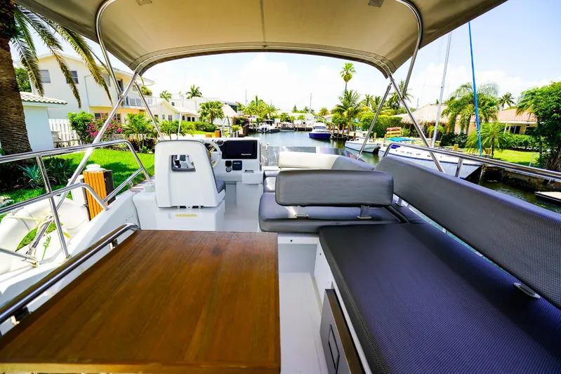 Queen Of Ark Yacht Photos Pics Flybridge view of 2017 Azimut 42 Fly yacht with seating and table, docked in a scenic canal.
