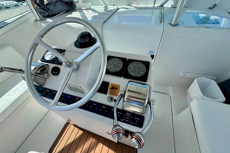  Yacht Photos Pics 2002 Luhrs 32 Open helm with steering wheel, gauges, and controls on teak flooring.