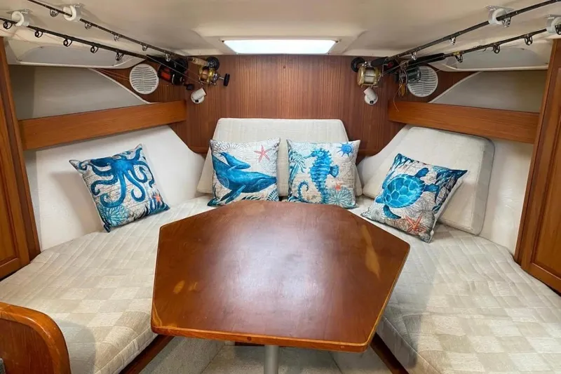  Yacht Photos Pics 2002 Luhrs 32 Open cabin interior with nautical-themed pillows and wooden table.